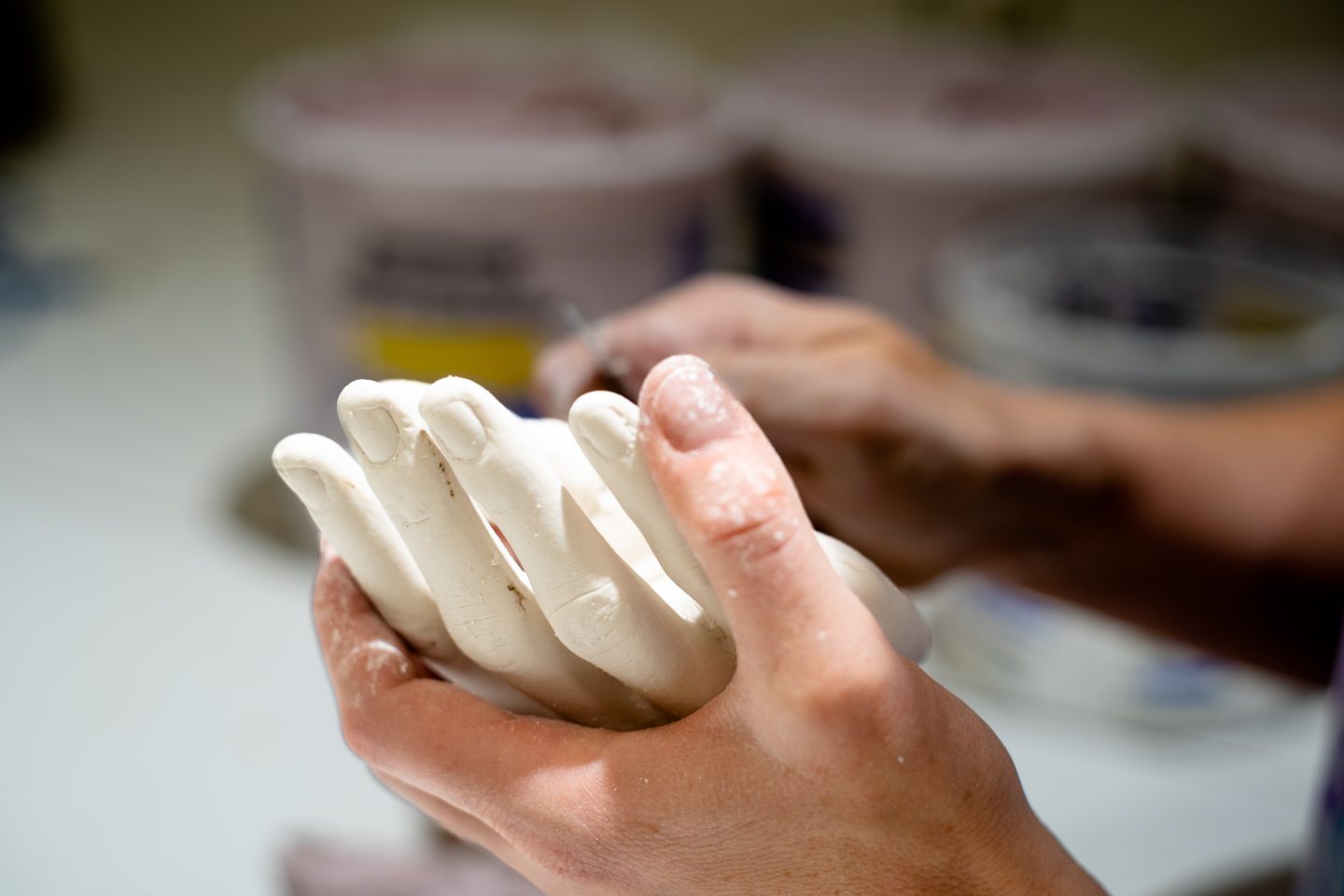 close-up of a hand shaping clay on a sculpture form in a studio at Anderson Ranch Arts Center